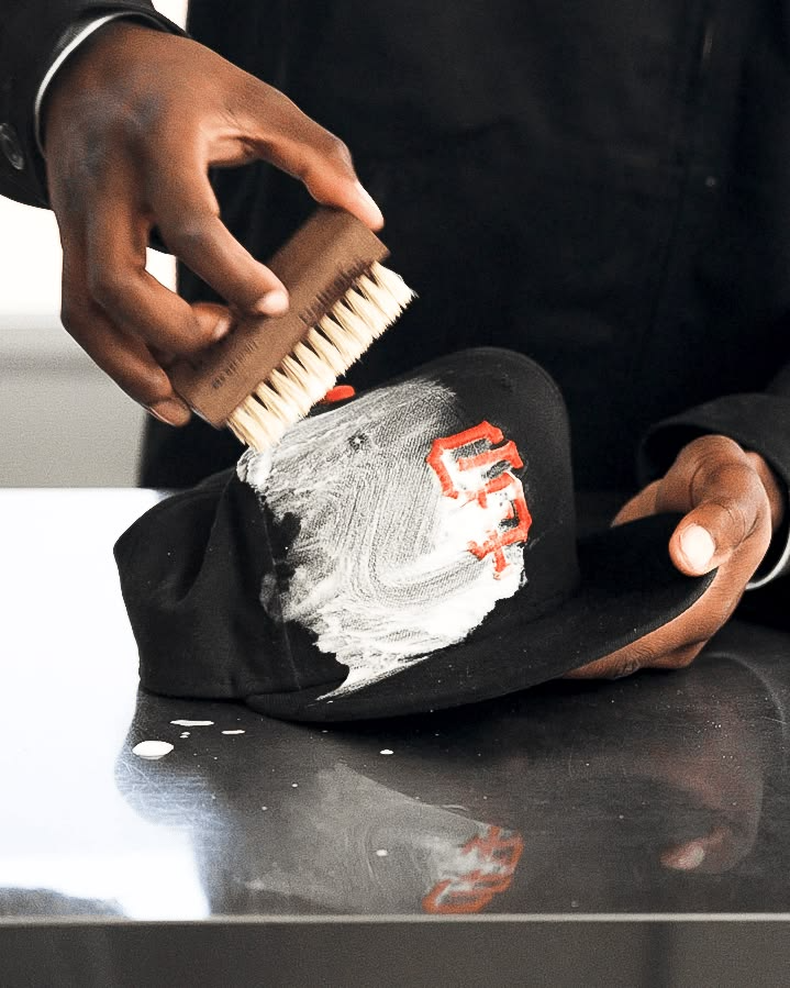 A structured cap resting crown-down on a clean surface next to a soft brush